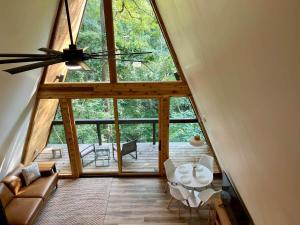 a living room with a ceiling fan and a table at Black Gum Getaway-Cozy Forest A-frame Near Bentonville in Rogers