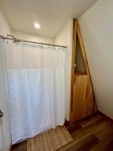 a bathroom with a shower curtain and a wooden door at Black Gum Getaway-Cozy Forest A-frame Near Bentonville in Rogers +19 photos