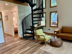 a living room with a spiral staircase and a chair at Running Spring Retreat-Cozy Forest A-Frame near Bentonville in Rogers