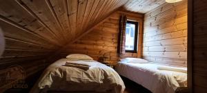 a bedroom with two beds in a log cabin at Chale do Avô Chico Penhas da Saúde in Penhas da Saúde