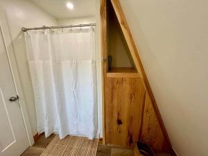 a bathroom with a shower with a white curtain at Running Spring Retreat-Cozy Forest A-Frame near Bentonville in Rogers