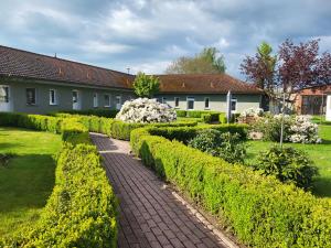 a brick path in a garden with bushes and a house at 15 Vogelnest - Hof Wiesengrund in Parchtitz