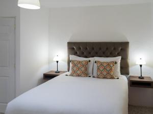 1 dormitorio con 1 cama blanca grande y 2 lámparas en In & Out Hotel, en Guatemala