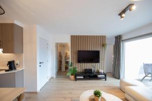 a living room with a couch and a tv at Appartement met zwembad in Neoportus Nieuwpoort in Nieuwpoort
