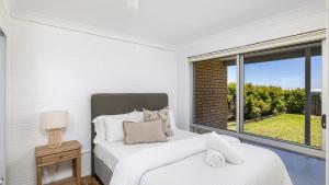 a white bedroom with a bed and a window at Absolute Birubi Beachfront in Anna Bay