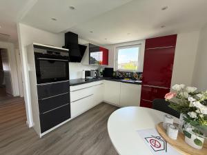 a kitchen with red and white cabinets and a table at Ferienwohnung Haus Grenzwald in Nettetal