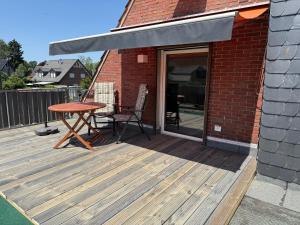 a wooden deck with a table and a patio at Ferienwohnung Haus Grenzwald in Nettetal