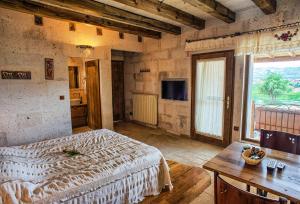 ein Schlafzimmer mit einem Bett, einem Tisch und einem Fenster in der Unterkunft Avanos Evi in Avanos