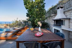 a wooden table on a patio with a fireplace at Great Escape Sea View Private Pools, Jacuzzi & Ultimate Relaxation in Maroulás