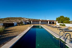 a swimming pool with chairs and a house at LAS DUNAS Caves - Olivo in Benamaurel