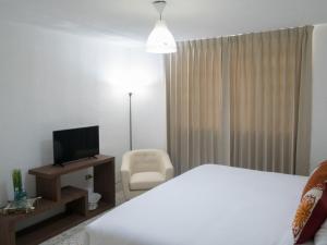 Habitación de hotel con cama, TV y silla en In & Out Hotel, en Guatemala