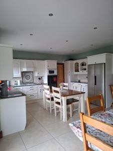 a kitchen with white cabinets and a table and chairs at Bree House Malin Head in Malin Head