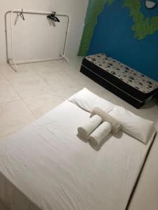 a white bed with two towels and a box on it at Flor de Lótus Privilege in Japaratinga