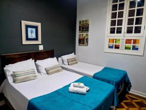 two beds in a hotel room with towels on them at Hotel Casa Grande Itapira in Itapira