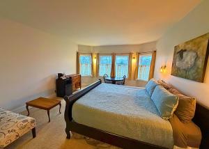 a bedroom with a bed and a table and windows at The Edenwild Boutique Inn in Lopez