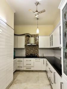 a kitchen with white cabinets and a ceiling fan at Sparra Homes in Gurgaon