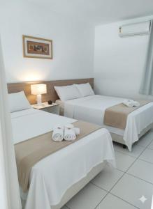 two beds in a hotel room with towels on them at Iloa Studio Alagoas conforto e encantamento in Barra de São Miguel