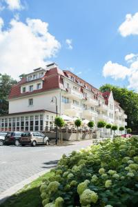 un gran edificio blanco con techo rojo en Hotel Cesarskie Ogrody en Świnoujście