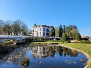 a white house with a bridge over a river at Kasteel Rosmeulen in Mall