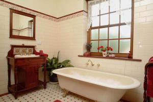 y baño con bañera, lavabo y espejo. en Amanda's Cottage 1899, en McLaren Vale