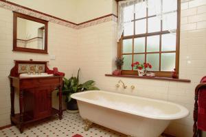 ein Badezimmer mit Badewanne, Waschbecken und Spiegel in der Unterkunft Amanda's Cottage 1899 in McLaren Vale