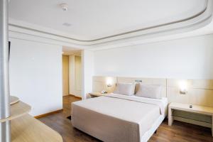 a bedroom with a large white bed and wooden floors at Alven Hotel by Slaviero Hotéis in Joinville