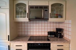 a kitchen with white cabinets and a stove top oven at Bungalow Friedrich in Thale