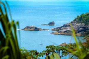 a view of the ocean with a boat in the water at VELINN Pousada 8 Ilhas in Ilhabela