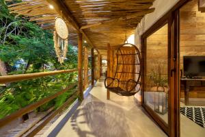 a porch of a house with a swing at Flamboyant Residence Quadrado in Trancoso