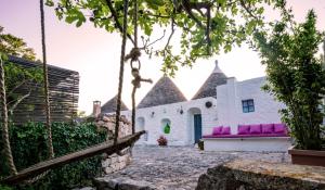 a white building with pink and purple pillows at Charming Trullo with Private Pool and Spa - Trullo Amarcord in Selva di Fasano