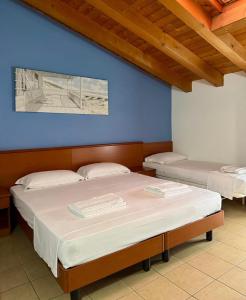 two beds in a room with a blue wall at Hotel Al Bosco in Sona +8 photos
