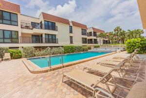 a swimming pool with lounge chairs and a building at Breezy Beachside Views! Heated Pool & Pickleball! in Holmes Beach