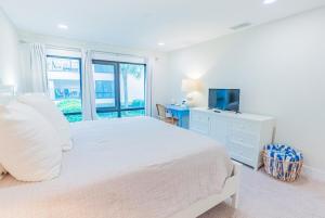 a white bedroom with a large bed and a television at Breezy Beachside Views! Heated Pool & Pickleball! in Holmes Beach +15 photos