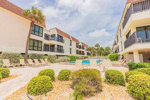 an apartment patio with chairs and a swimming pool at Breezy Beachside Views! Heated Pool & Pickleball! in Holmes Beach