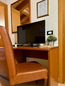 a computer monitor sitting on a desk with a chair at Hotel Al Bosco in Sona