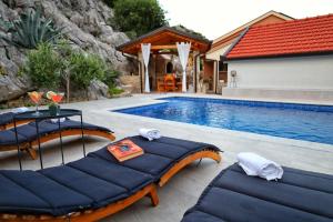 a pool with two lounge chairs and a table next to it at Cliffside Villa Vilić in Vrgorac
