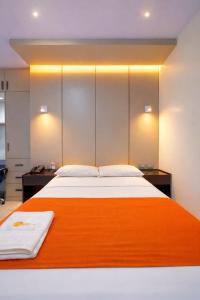 a bedroom with a large bed with an orange blanket at Hotel Madrigal in Portoviejo