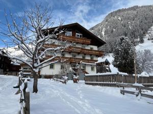 a large building in the snow with a tree at Bergerhof in Kals am Großglockner