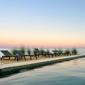 a row of benches sitting next to a body of water at LAS DUNAS Caves - Olivo in Benamaurel