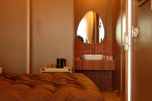 a bathroom with a bed and a sink and a mirror at Hale Homestay in Ấp Thanh Sơn (1)
