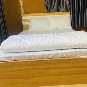 a bed with white sheets and pillows on it at Farm Tân Tiến in Ấp Bình Thạnh