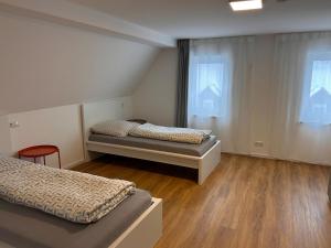 two beds in a room with wooden floors and windows at Groß Höpper in Albertshofen