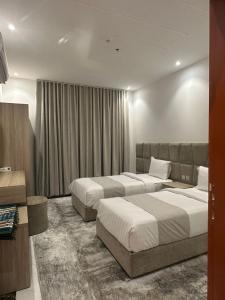 a hotel room with two beds and a couch at جميرا محايل in Muhayil
