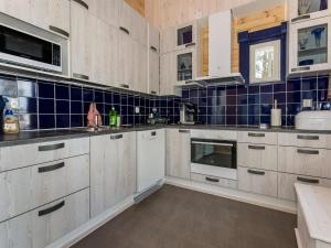 a kitchen with white cabinets and blue tiles on the wall at Holiday Home Klippan by Interhome in Tuuhonen +35 photos
