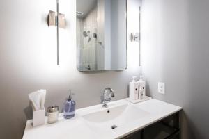 a white bathroom with a sink and a mirror at Hollyhock Suite 403 in Louisville