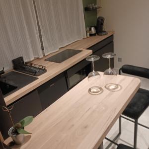 a kitchen with a wooden table with two wine glasses on it at Suite Zen Balnéo in Montpellier
