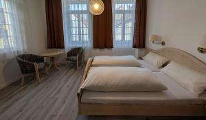 a bedroom with two beds and a table and windows at Serviced Rooms ''Krone'' in Creglingen