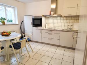 a kitchen with white cabinets and a table and a sink at Ferienhaus Iris in Radolfzell am Bodensee
