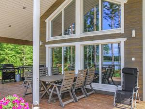 a porch with a wooden table and chairs and windows at Holiday Home Kielo by Interhome in Pertunmaa