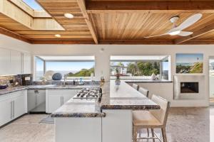 a kitchen with white cabinets and a wooden ceiling at Encinitas Shores - Beachfront, Ocean View & Patio in Encinitas
